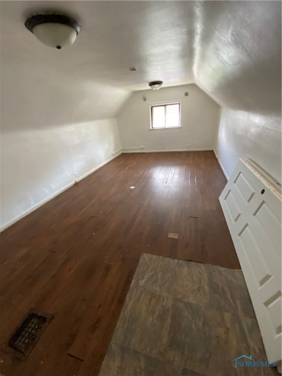 additional living space with hardwood / wood-style floors and vaulted ceiling