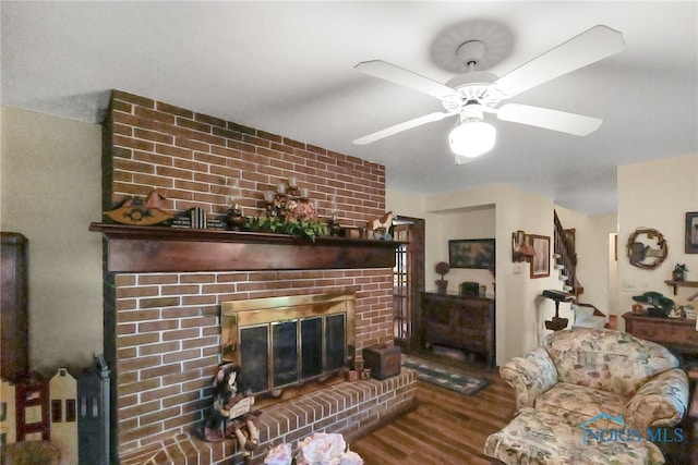 living room with a fireplace, wood-type flooring, and ceiling fan