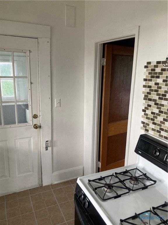 kitchen featuring tasteful backsplash, white range with gas cooktop, and dark tile patterned floors