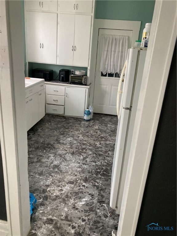 kitchen with white cabinetry and white fridge