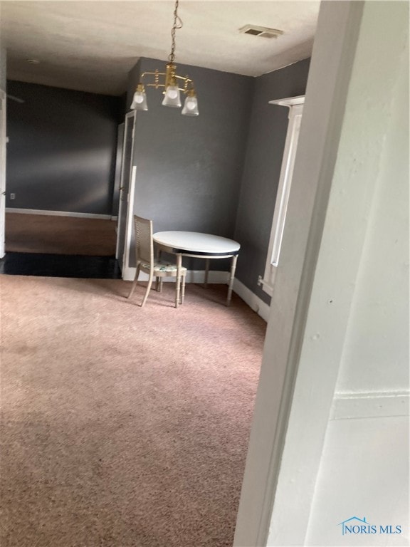 unfurnished dining area with carpet and a chandelier