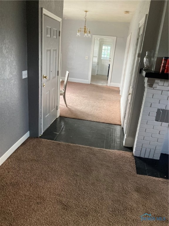 corridor featuring dark carpet and a chandelier