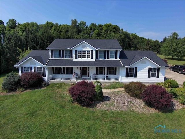 view of front of home featuring covered porch, a front yard, and a forest view