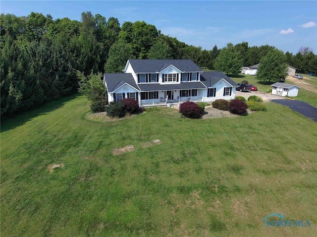 view of front of home with a front yard, a porch, a wooded view, and aphalt driveway