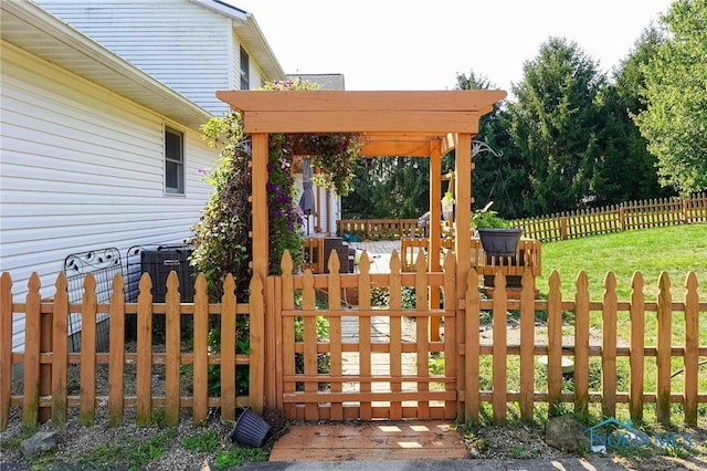 view of gate with fence private yard and a lawn