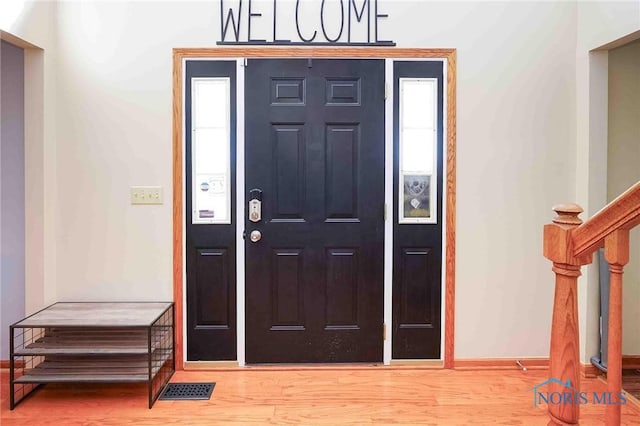 entrance foyer featuring visible vents, baseboards, stairway, and wood finished floors