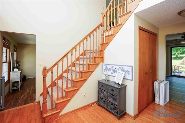 stairs with baseboards, ceiling fan, a textured ceiling, radiator, and wood finished floors