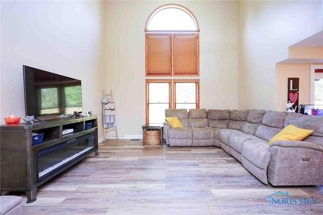 living room with a towering ceiling and wood finished floors