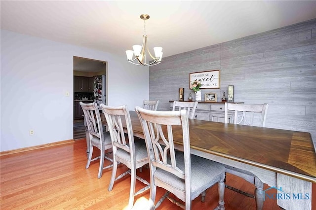 dining area featuring a chandelier, baseboards, and light wood-style flooring