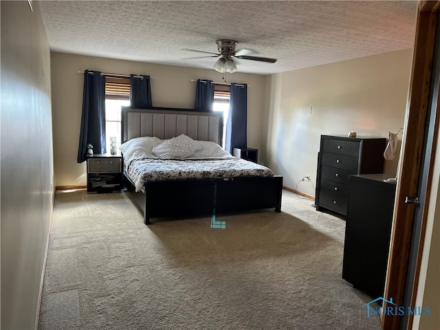 carpeted bedroom with a textured ceiling, ceiling fan, and multiple windows