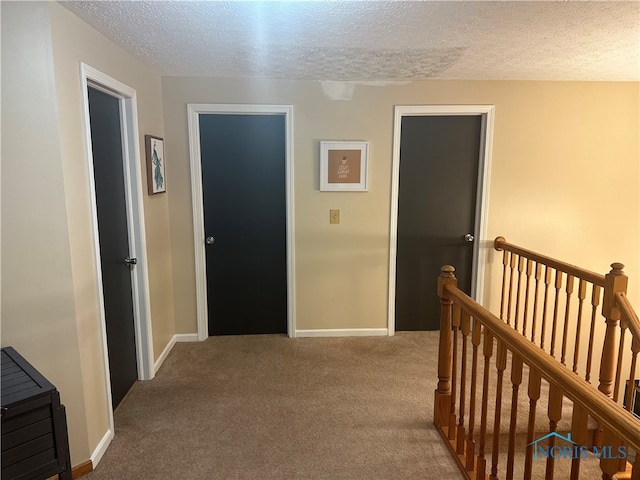 hallway with light carpet and a textured ceiling