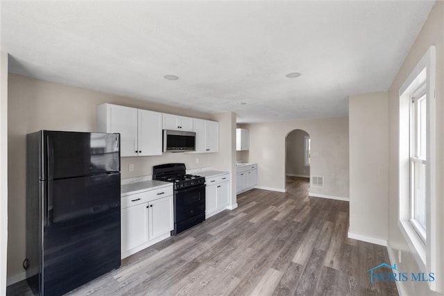 kitchen featuring light wood-type flooring, black appliances, and white cabinetry