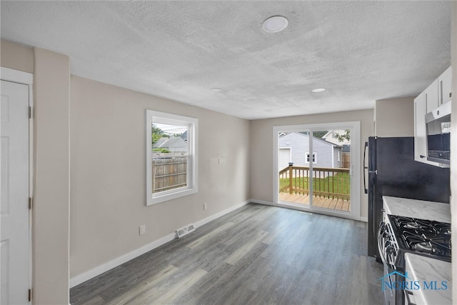 kitchen with hardwood / wood-style floors, appliances with stainless steel finishes, a textured ceiling, and white cabinets