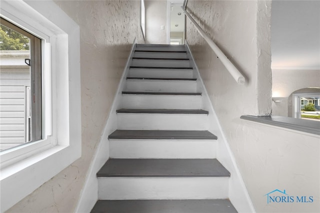 staircase with a healthy amount of sunlight and ornamental molding