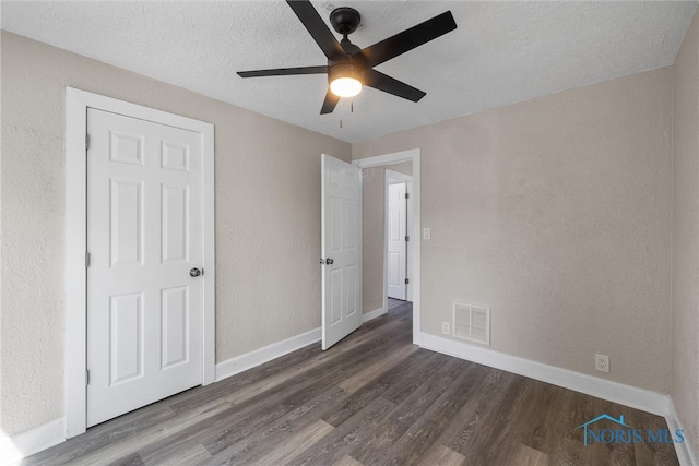 unfurnished bedroom featuring a textured ceiling, dark wood-type flooring, and ceiling fan