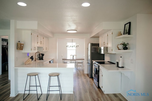 kitchen with kitchen peninsula, a kitchen breakfast bar, stainless steel appliances, and light hardwood / wood-style floors