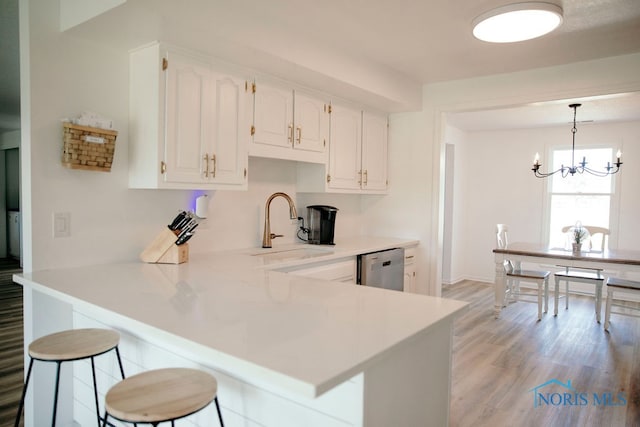 kitchen featuring light hardwood / wood-style floors, white cabinetry, kitchen peninsula, and hanging light fixtures