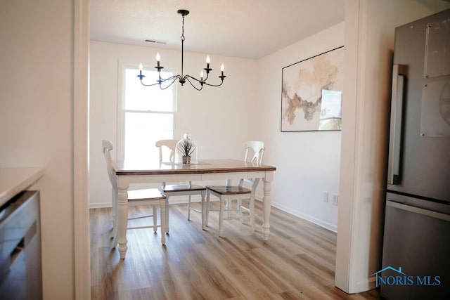 dining space featuring light wood-type flooring and an inviting chandelier