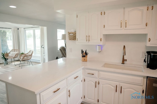 kitchen with white cabinets, hardwood / wood-style flooring, sink, kitchen peninsula, and stainless steel dishwasher