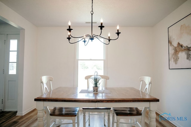 dining space featuring dark hardwood / wood-style floors, an inviting chandelier, and a healthy amount of sunlight