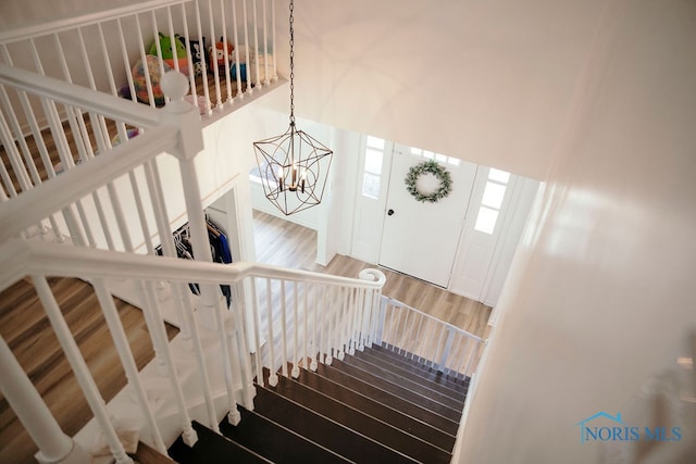 stairway featuring hardwood / wood-style floors and an inviting chandelier