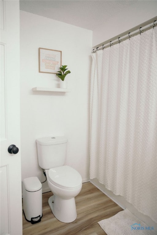 bathroom featuring a shower with curtain, toilet, and hardwood / wood-style flooring