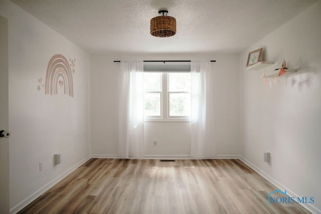 unfurnished room featuring a textured ceiling and light wood-type flooring