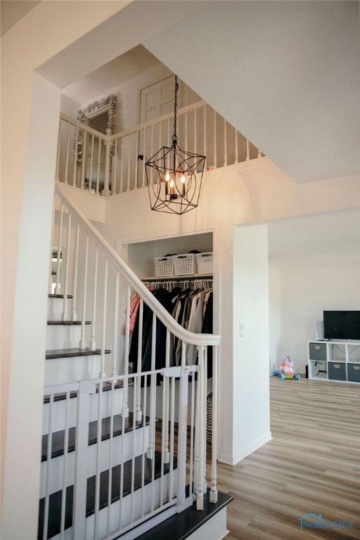 stairway with an inviting chandelier and hardwood / wood-style flooring