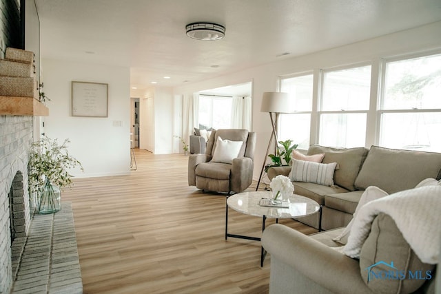 living room featuring light wood-type flooring, plenty of natural light, and a fireplace