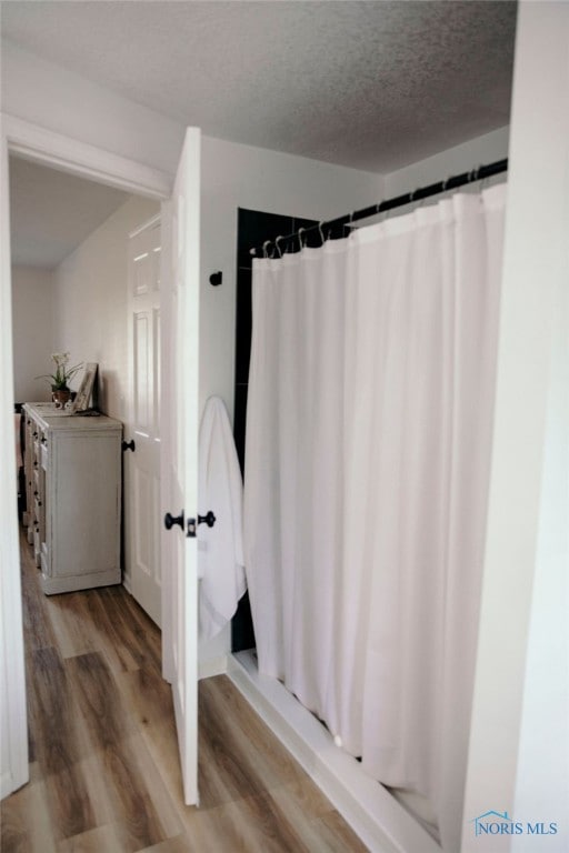 bathroom with curtained shower, wood-type flooring, vanity, and a textured ceiling