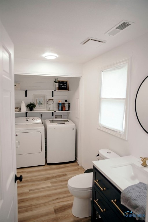 bathroom with independent washer and dryer, toilet, hardwood / wood-style floors, and vanity