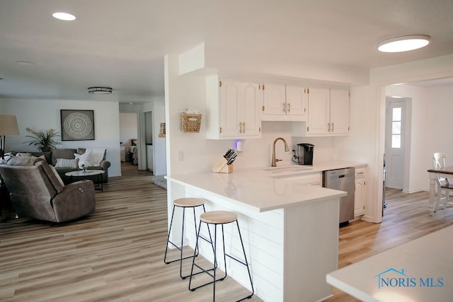 kitchen with dishwasher, light hardwood / wood-style floors, a breakfast bar, kitchen peninsula, and white cabinetry