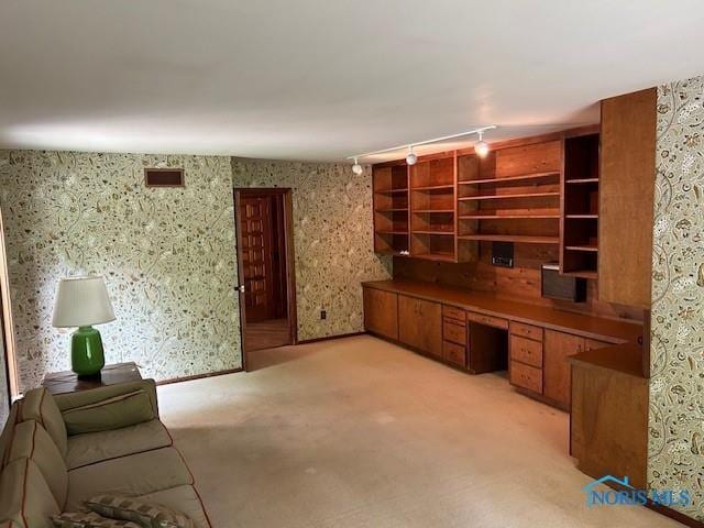 unfurnished office with light colored carpet, visible vents, built in study area, track lighting, and wallpapered walls