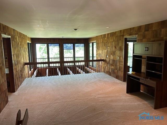 unfurnished bedroom featuring carpet floors and wooden walls