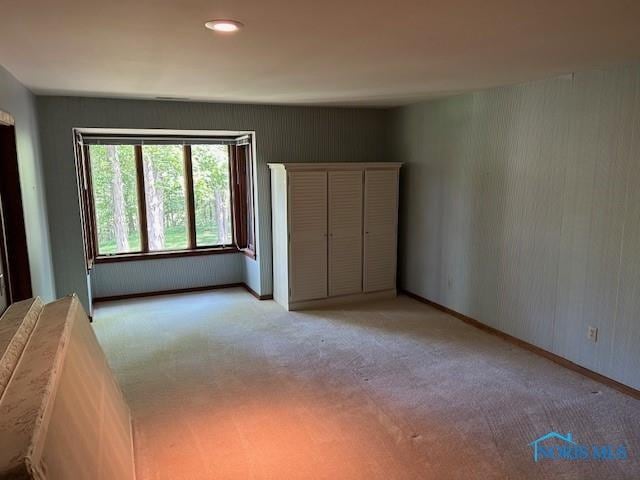 unfurnished bedroom featuring light carpet and baseboards