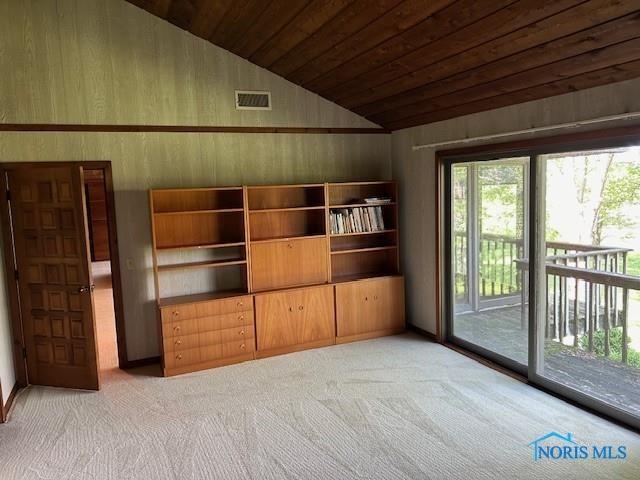 unfurnished living room featuring carpet, vaulted ceiling, wood walls, and wooden ceiling