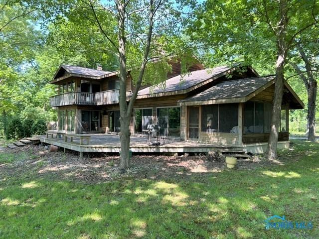 back of house featuring a wooden deck, a lawn, and a sunroom