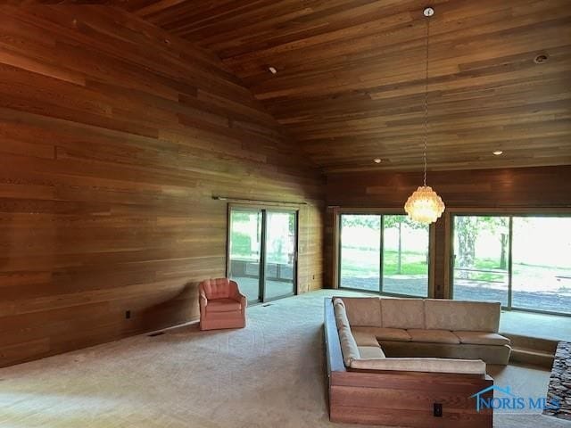 unfurnished living room with wood ceiling, high vaulted ceiling, carpet flooring, and wooden walls