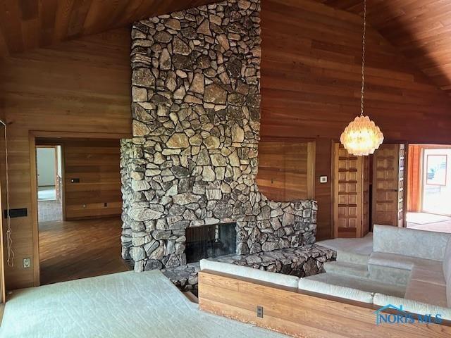 unfurnished living room featuring wood ceiling, wooden walls, an inviting chandelier, and a stone fireplace