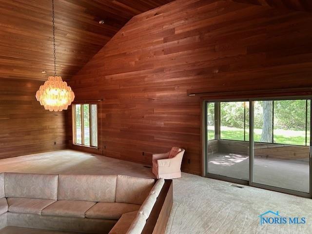 unfurnished bedroom featuring carpet floors, wood ceiling, wooden walls, high vaulted ceiling, and access to outside