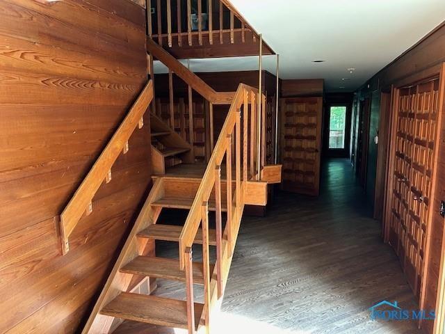 stairway with wood walls and wood finished floors
