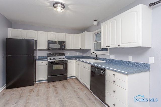 kitchen featuring sink, white cabinets, black appliances, and light hardwood / wood-style flooring