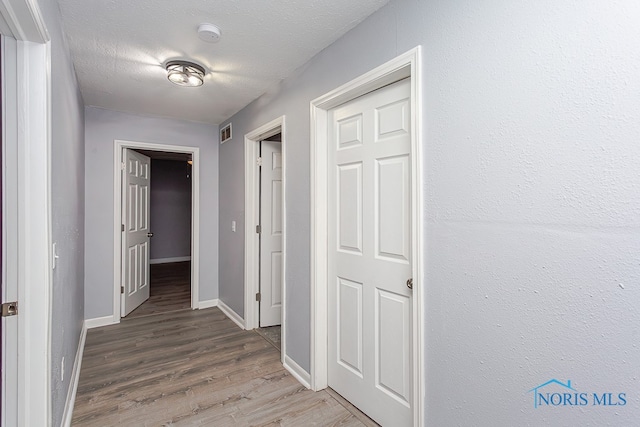 hall featuring wood-type flooring and a textured ceiling