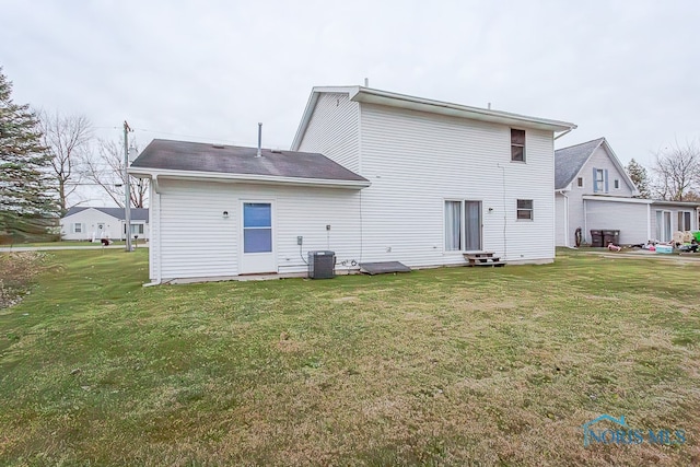 rear view of property featuring a lawn and central air condition unit