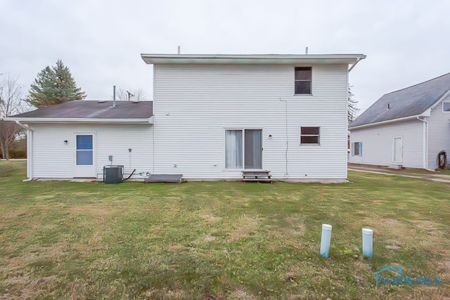 back of house with central AC unit and a yard