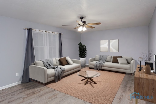 living room featuring hardwood / wood-style flooring, ceiling fan, and a textured ceiling