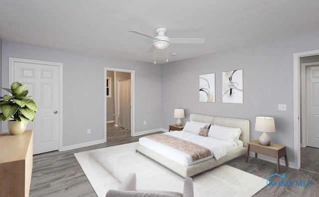 bedroom with a textured ceiling, connected bathroom, dark hardwood / wood-style floors, and ceiling fan