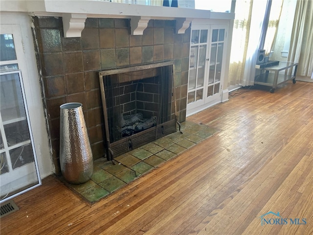 interior details with wood-type flooring, beverage cooler, and a tile fireplace