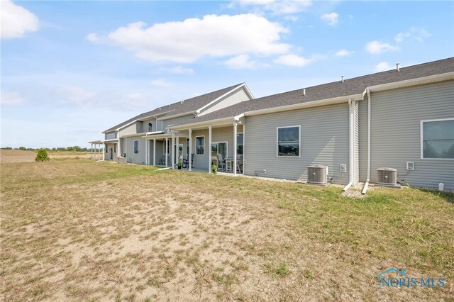 rear view of house with a yard and cooling unit