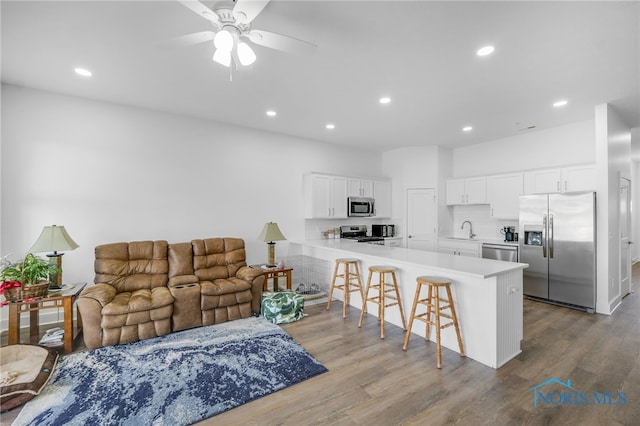 kitchen with a breakfast bar area, light hardwood / wood-style floors, stainless steel appliances, sink, and kitchen peninsula